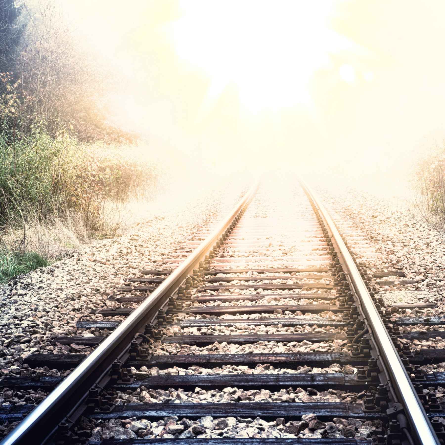 a train track fading into a bright light in the distance